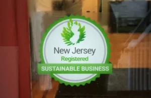 Sticker on a window showing a green leaf emblem with text "New Jersey Registered Sustainable Business," promoting eco-friendly practices.